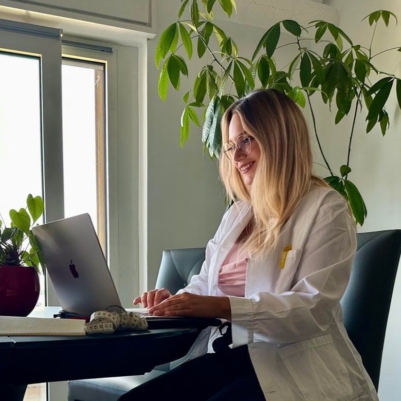 Giulia Rogai in camice bianco, sorridente, al computer nel suo studio